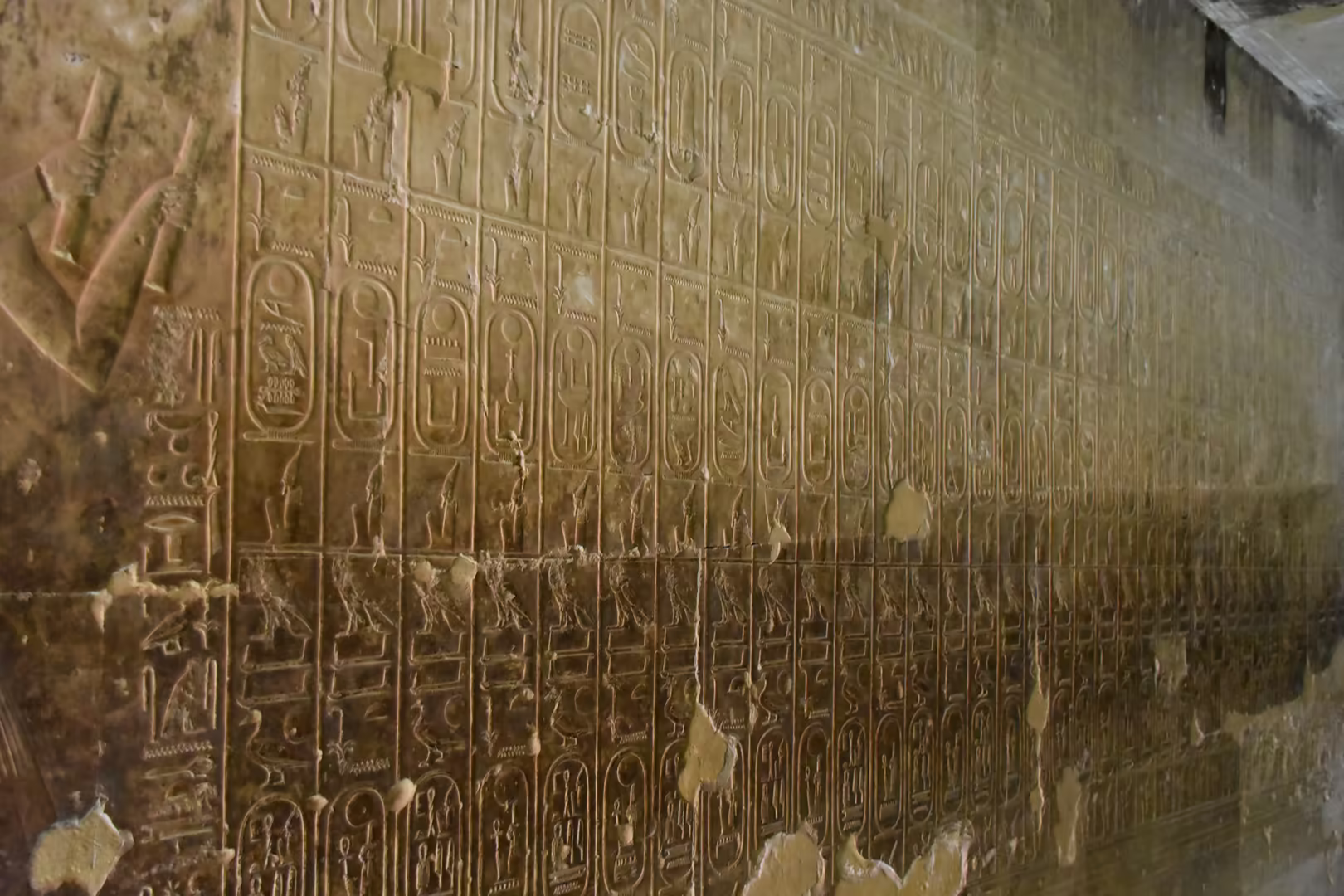 Eine Sandsteinwand mit dicht gesetzten Hieroglyphen in Reihen.