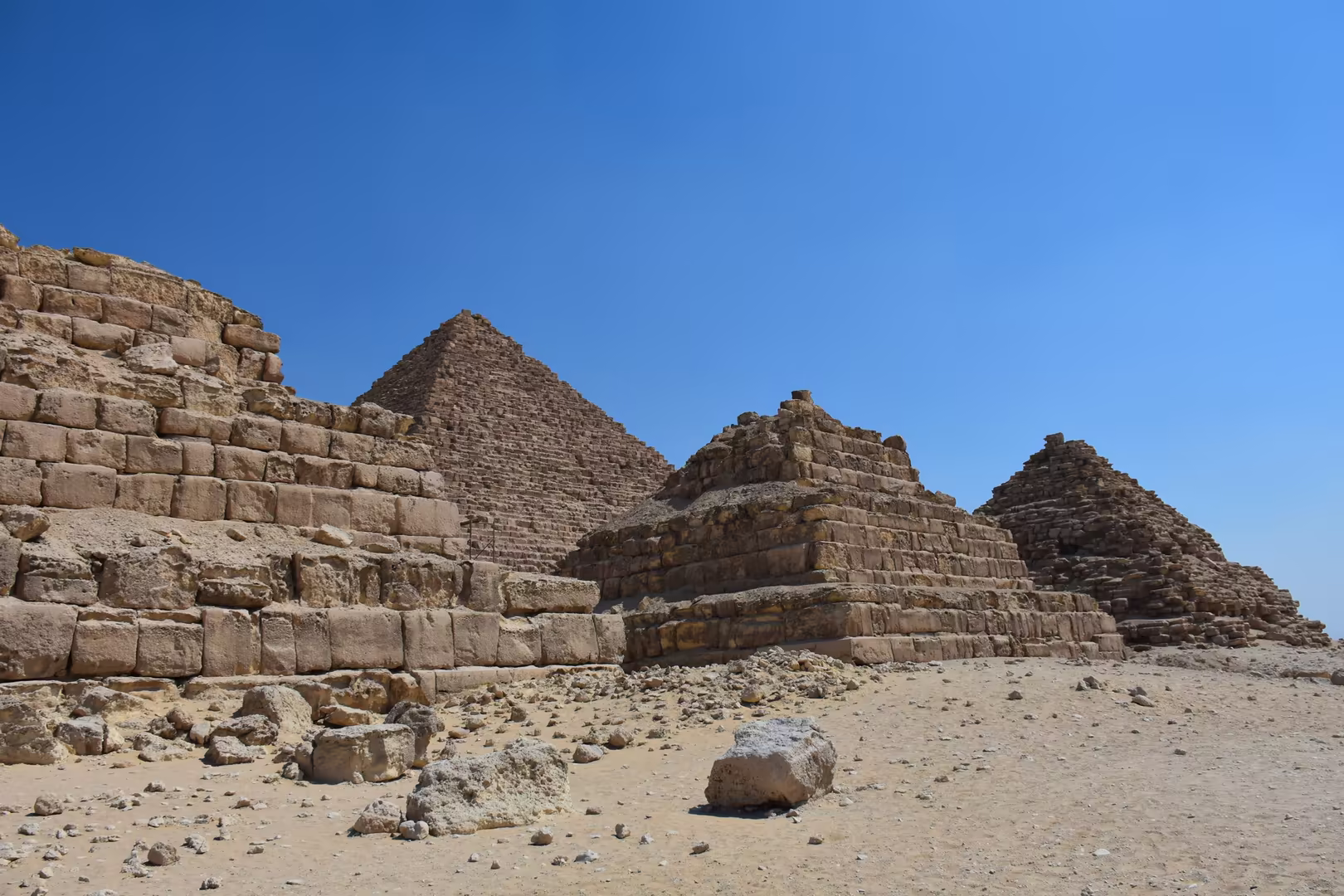 Die Pyramide des Mykerinos mit ihren Königinnenpyramiden, dahinter die Wüste.