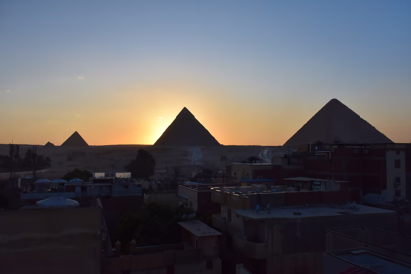 Die Pyramiden als dunkle Silhouetten vor einem warmen Abendhimmel.