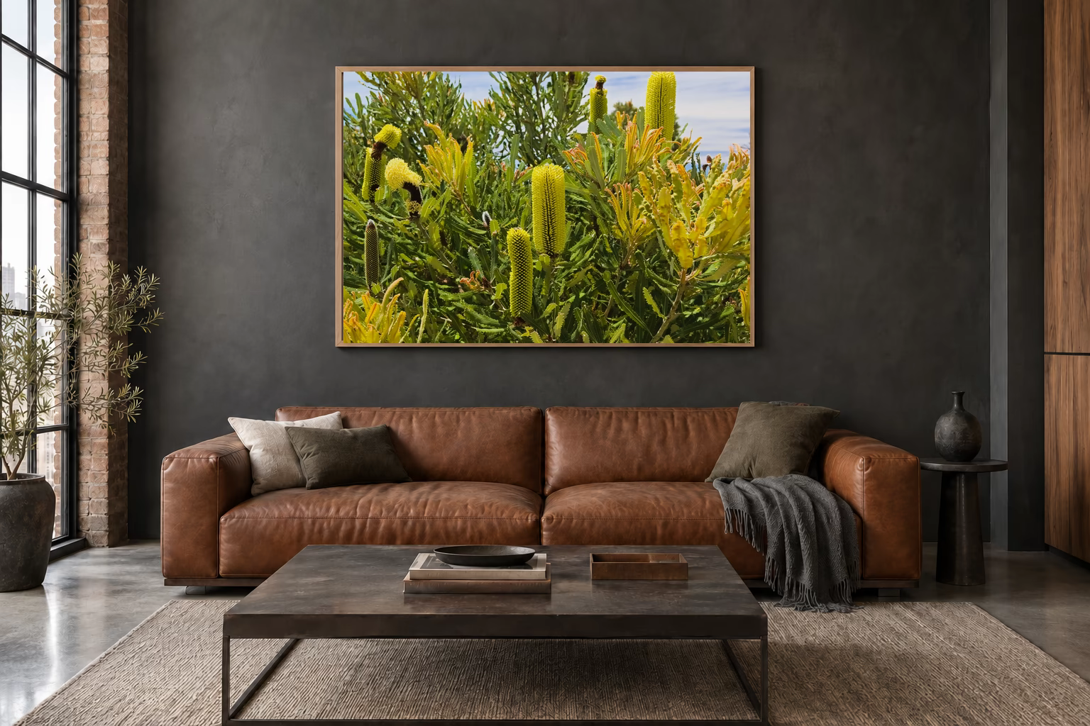 Das Werk an einer dunklen Wand im Loft über einem Ledersofa: Banksia im Küstenlicht, 120 × 80 cm.