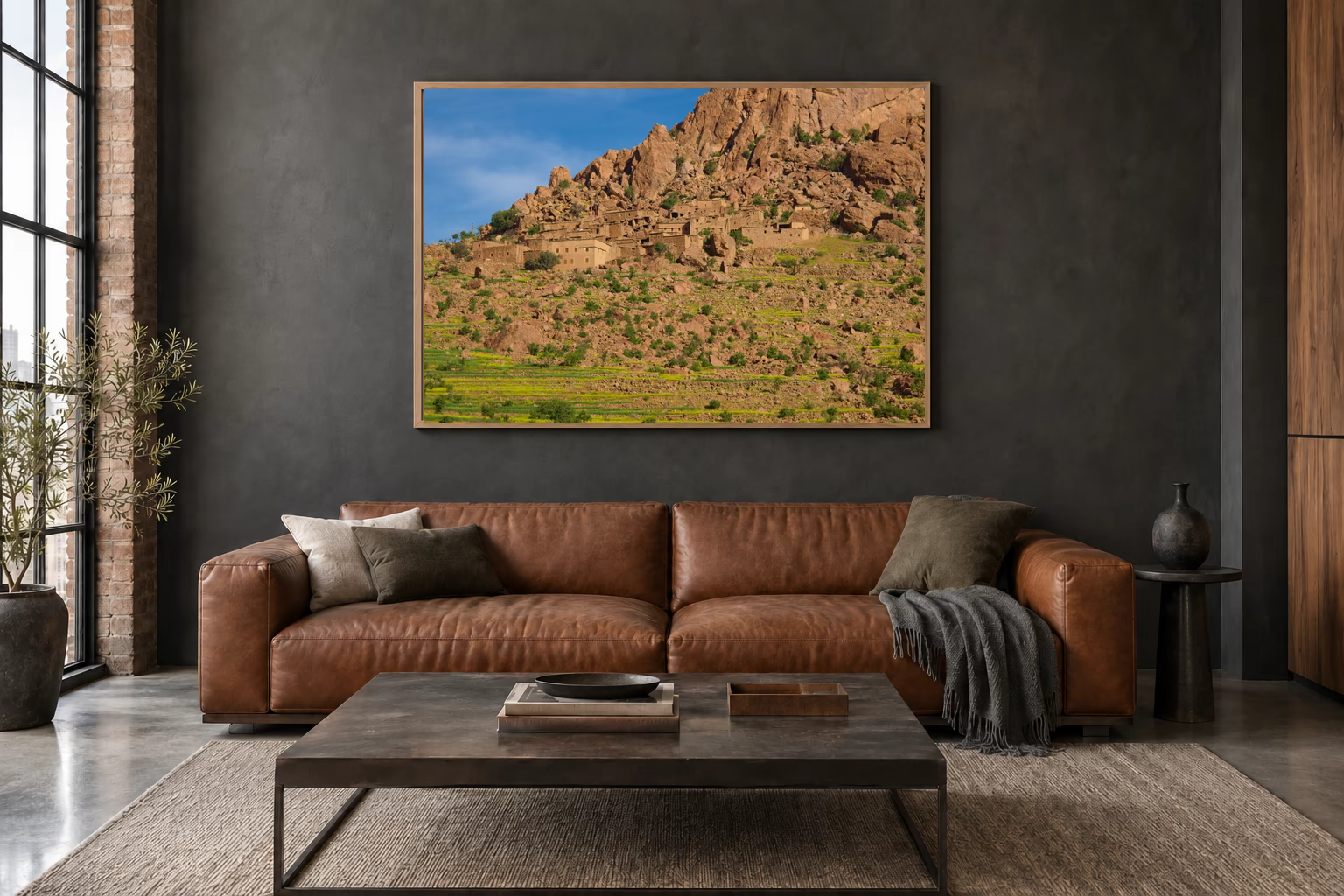 Das Werk an einer dunklen Wand im Loft über einem Ledersofa: Dorf am Fels, 120 × 80 cm.