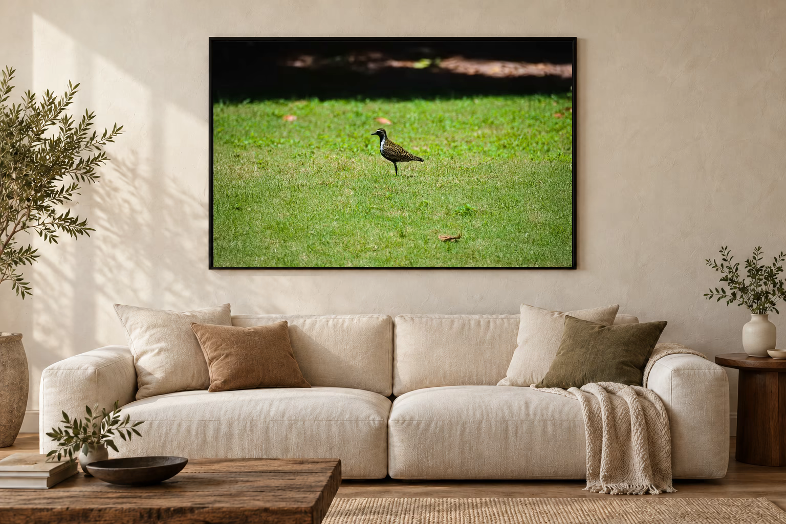 Das Werk an einer hellen Wohnzimmerwand über einem Sofa: Ein Vogel auf dem Rasen im Rahmen, 120 × 80 cm.