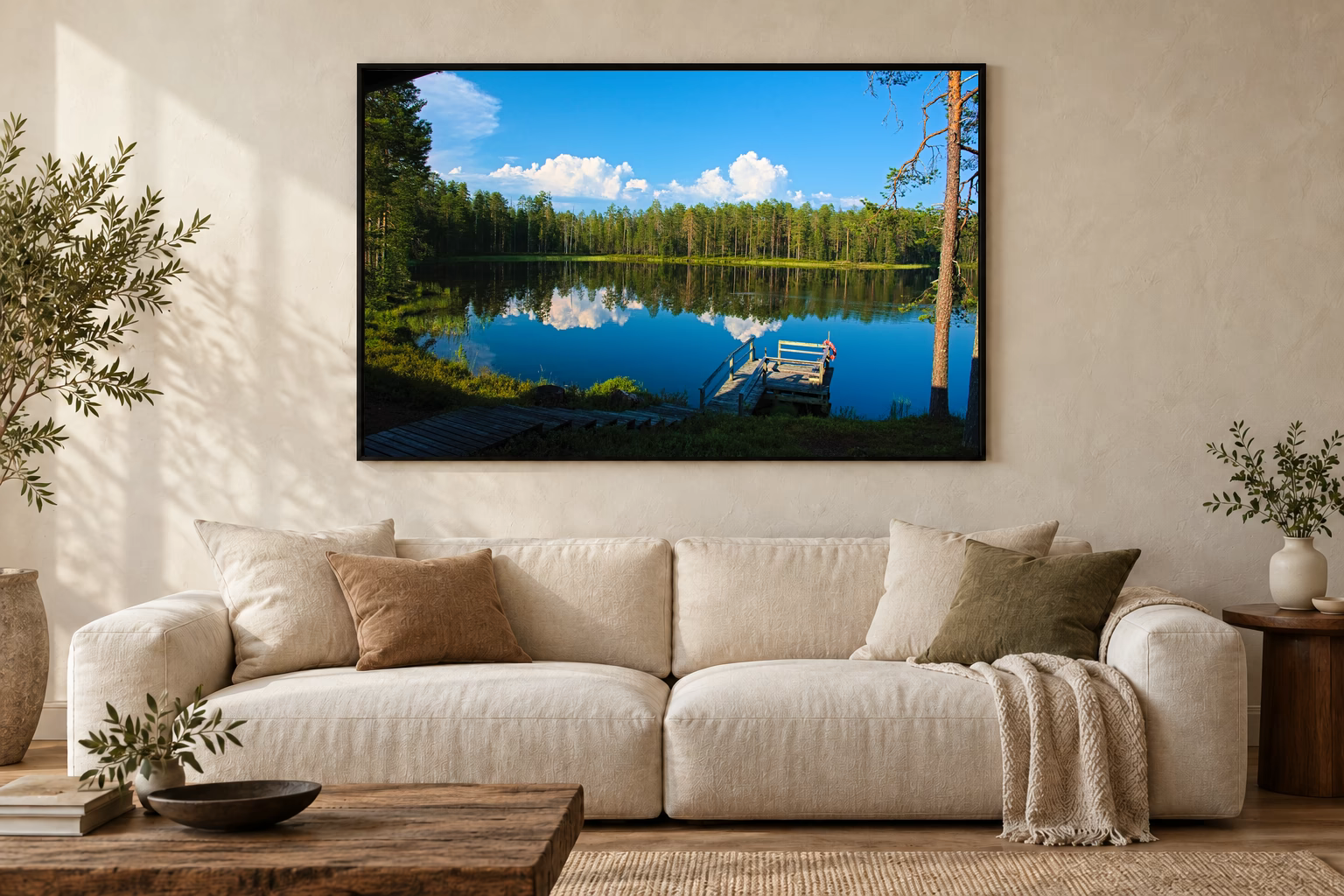 Das Werk an einer hellen Wohnzimmerwand über einem Sofa: Finnischer See mit Steg im Rahmen, 120 × 80 cm.