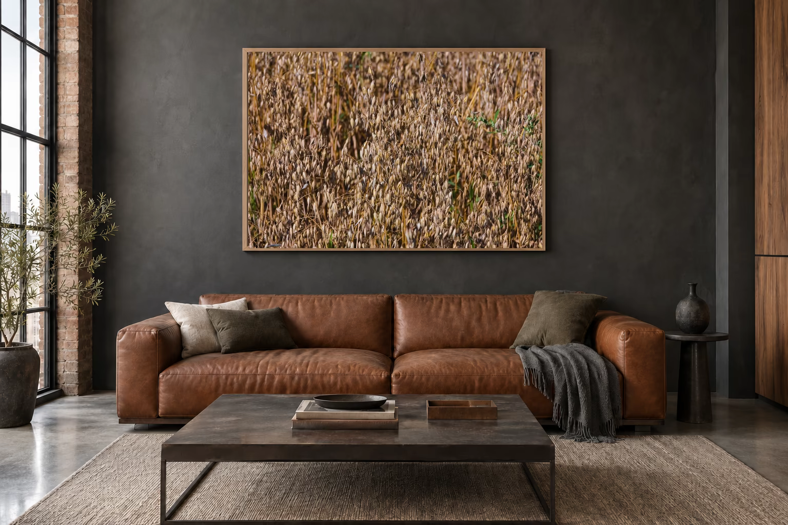 Das Werk an einer dunklen Wand im Loft über einem Ledersofa: Haferfeld im Morgenlicht, 120 × 80 cm.