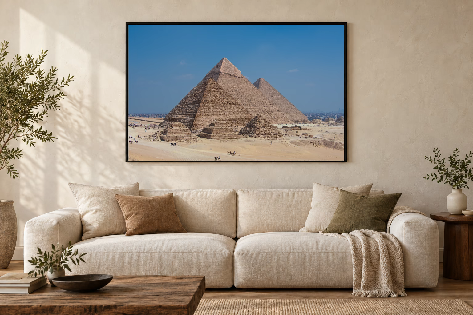 Das Werk an einer hellen Wohnzimmerwand über einem Sofa: Kamele vor den Pyramiden im Rahmen, 120 × 80 cm.