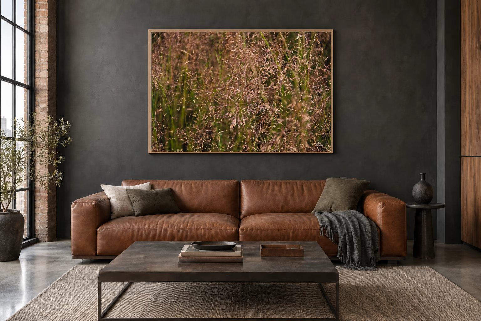 Das Werk an einer dunklen Wand im Loft über einem Ledersofa: Sommergras im Abendlicht, 120 × 80 cm.