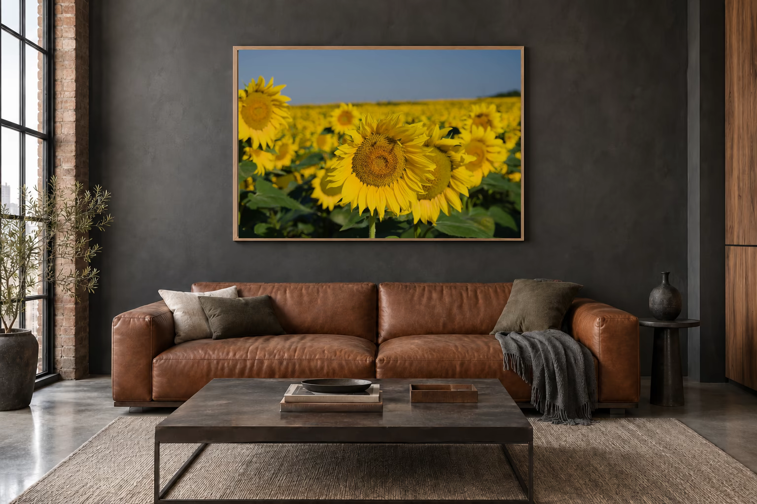 Das Werk an einer dunklen Wand im Loft über einem Ledersofa: Sonnenblumen bis zum Horizont, 120 × 80 cm.