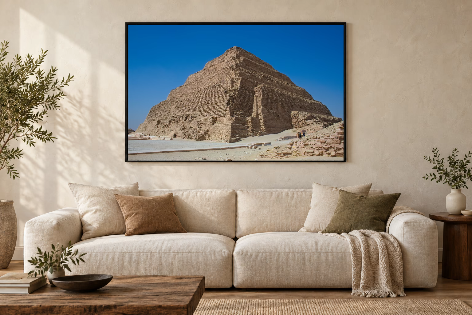 Das Werk an einer hellen Wohnzimmerwand über einem Sofa: Zwei Figuren an der Stufenpyramide im Rahmen, 120 × 80 cm.